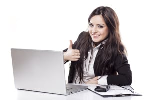 smiling  business woman at desk with laptop showing thumbs up